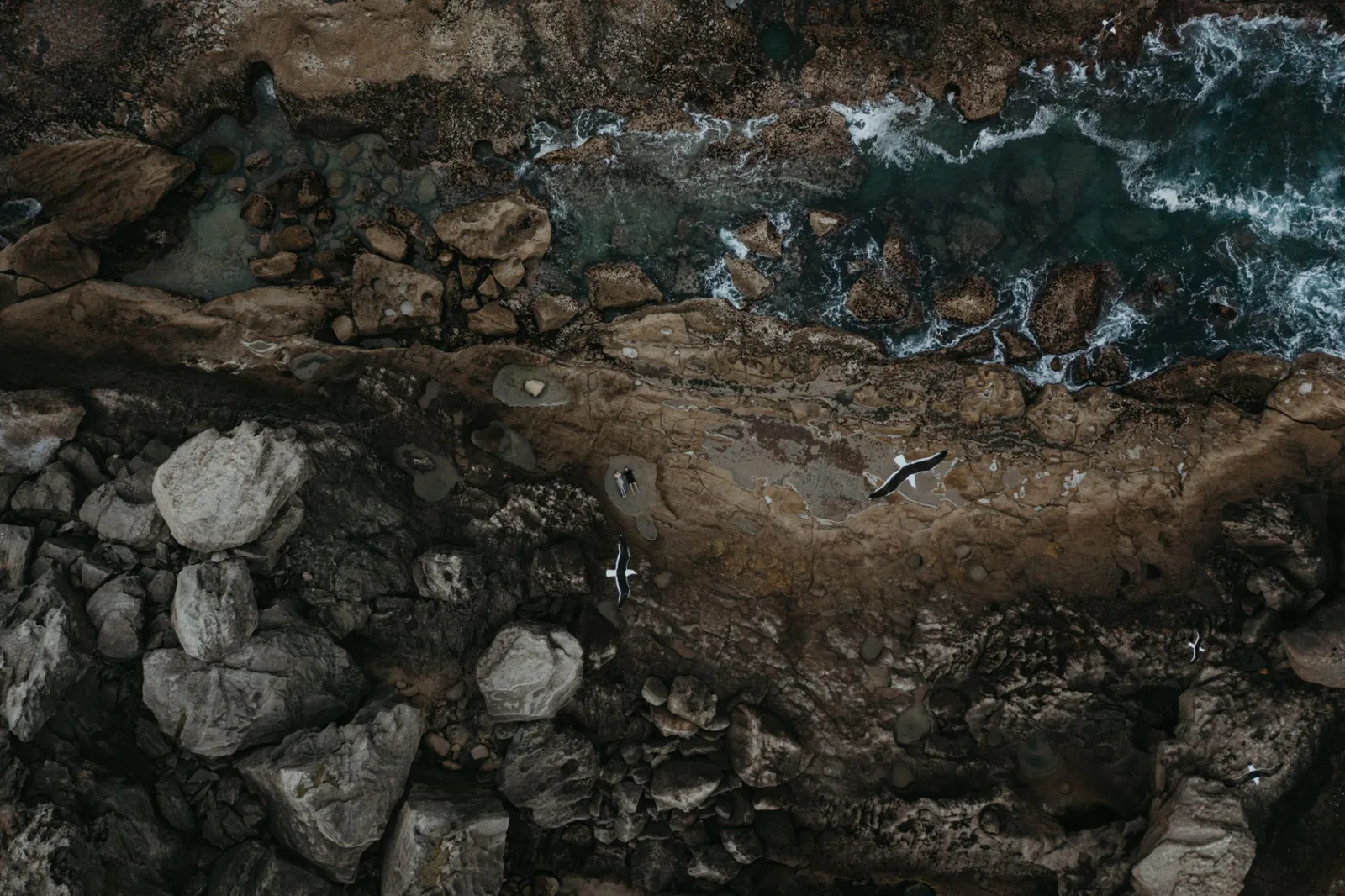 A couple seen from above among the rocks and ocean at Robberg